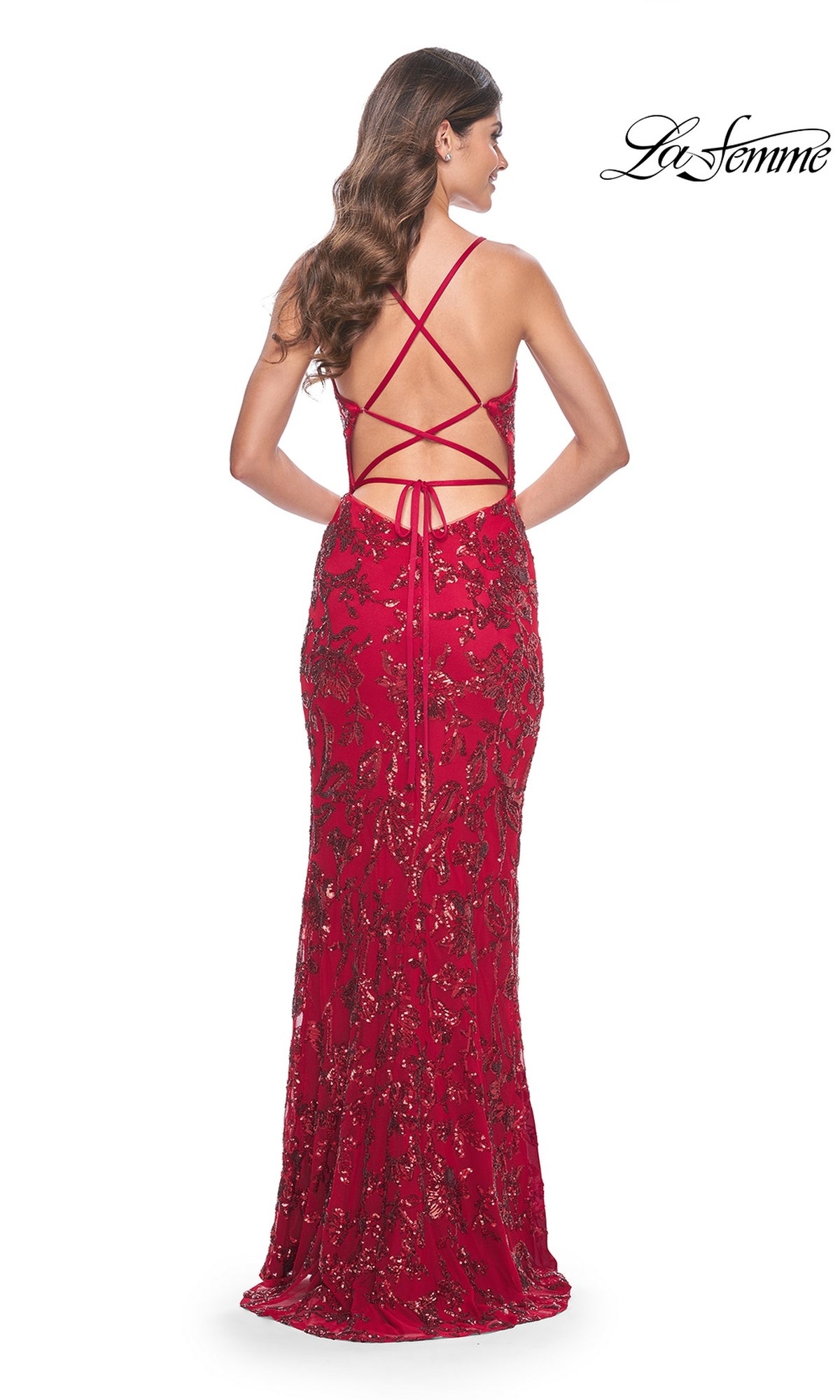 A woman wears the La Femme Sequin-Print Long Fitted Prom Dress 31933 in red, featuring a floor-length fitted silhouette with sequins and a crisscross open back. The
